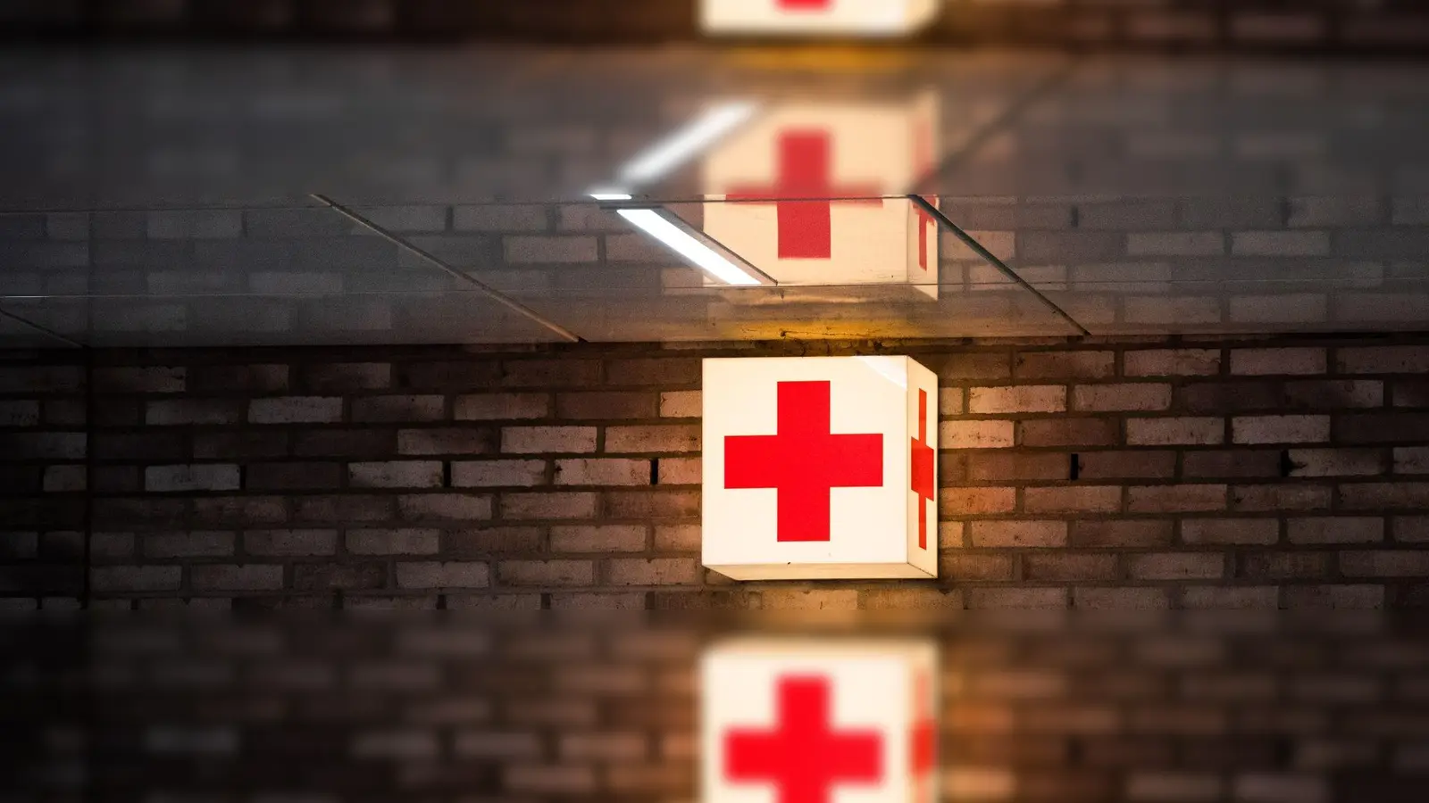 Ein Leuchtkasten mit einem roten Kreuz hängt vor der Notaufnahme eines Krankenhauses. (Foto: Julian Stratenschulte/dpa/Symbolbild)