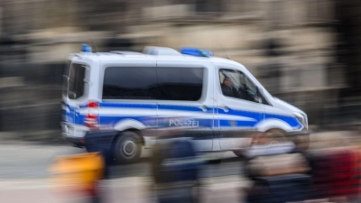 Ein Einsatzwagen der Polizei fährt durch eine Stadt. (Foto: Robert Michael/dpa/Symbolbild)