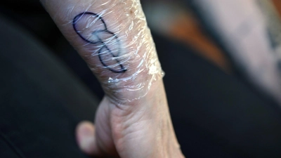 Creme und Folie schützen ein frisch gestochenes OPT.INK-Tattoo auf einem Unterarm. (Foto: Pia Bayer/dpa/Archivbild)