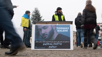 Protestaktion gegen Irans Staatsführung auf dem Pariser Platz in Berlin. Auf dem Plakat ist der Rapper Salehi zu sehen. (Foto: Paul Zinken/dpa)