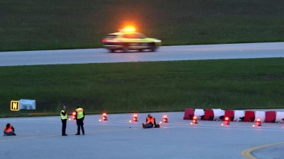 Klimaaktivisten haben sich am frühen Morgen auf einer Zufahrt für Start- und Landebahnen am Flughafen Franz-Josef-Strauß festgeklebt. (Foto: Karl-Josef Hildenbrand/dpa)