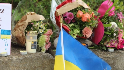 Am Gelände eines Einkaufszentrums, an dem am Samstagabend (27.04.2024) zwei Männer aus der Ukraine getötet worden sind, wurden Blumen niedergelegt, sowie eine kleine ukrainische Flagge aufgestellt. (Foto: Constanze Wilz/dpa)