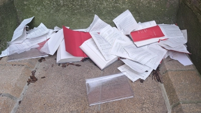 In einer Ecke an der Außenseite der Kirche liegen die zerrissenen Gotteslob-Bücher. (Foto: Daniel Bittel)
