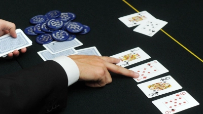 Der Dealer deutet beim Poker auf zwei aufgedeckte Karten. (Foto: Tobias Hase/dpa/Symbolbild)
