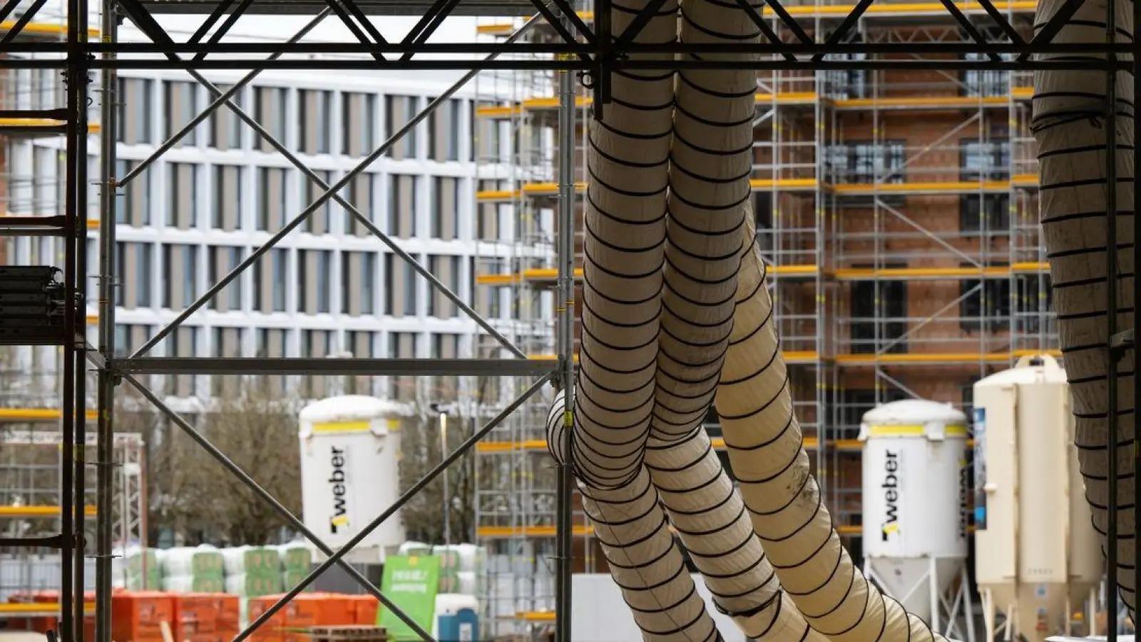 Ein Gerüst und Baumaterial sind auf der Baustelle eines Neubaus zu sehen. (Foto: Sven Hoppe/dpa)