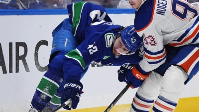 Quinn Hughes von den Vancouver Canucks wird von Ryan Nugent-Hopkins von den Edmonton Oilers zu Fall gebracht. (Foto: Darryl Dyck/The Canadian Press via AP/dpa)