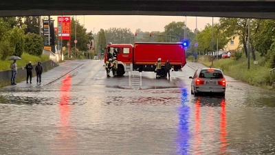 Ein Einsatzfahrzeug der Feuerwehr sichert eine mit Regenwasser vollgelaufene Unterführung ab. (Foto: Ferdinand Merzbach/News5/dpa)