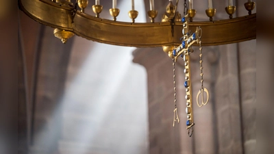 Ein Kreuz hängt an einem Leuchter im Altarbereich des Bamberger Doms. (Foto: Daniel Vogl/dpa)