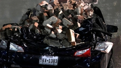 Ein Auto, das von herabfallenden Ziegeln einer umgestürzten Hauswand zerquetscht wurde, steht auf einem Parkplatz in der Innenstadt von Houston. (Foto: David J. Phillip/AP/dpa)