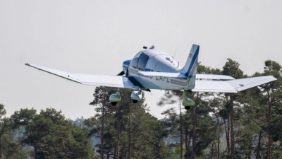 Ein Motorflugzeug fliegt über Bäumen. (Foto: Pia Bayer/dpa)