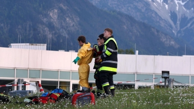 Einsatzkräfte der Feuerwehr stehen vor der abgeriegelten Notaufnahme des Unfallklinikums Murnau. (Foto: Karl-Josef Hildenbrand/dpa)
