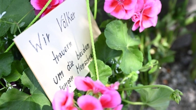 Neben dem Einkaufszentrums an dem am Samstagabend zwei Männer aus der Ukraine getötet worden sind, haben Menschen Blumen und Plakate niedergelegt. Die beiden getötete Ukrainer waren Armeeangehörige. (Foto: Angelika Warmuth/dpa)