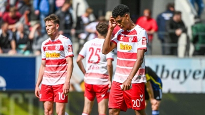 Die Mannschaft von Regenburg steht nach dem mit 0:1 verlorenen Spiel gegen Saarbrücken auf dem Rasen. (Foto: Armin Weigel/dpa)