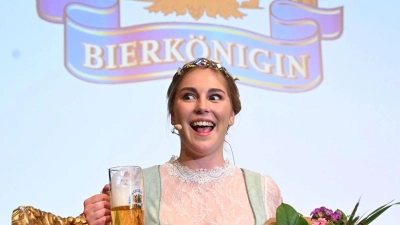 Linnea Klee, die neu gewählte Bierkönigin, sitzt mit einem Bier auf der Bühne beim Festabend zur Wahl der Bayerischen Bierkönigin 2024/25 im Löwenbräukeller. (Foto: Felix Hörhager/dpa)