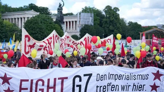 Teilnehmer stehen mit einem Banner mit der Aufschrift &quot;Fight G7&quot; auf der Theresienwiese. (Foto: Michael Kappeler/dpa)
