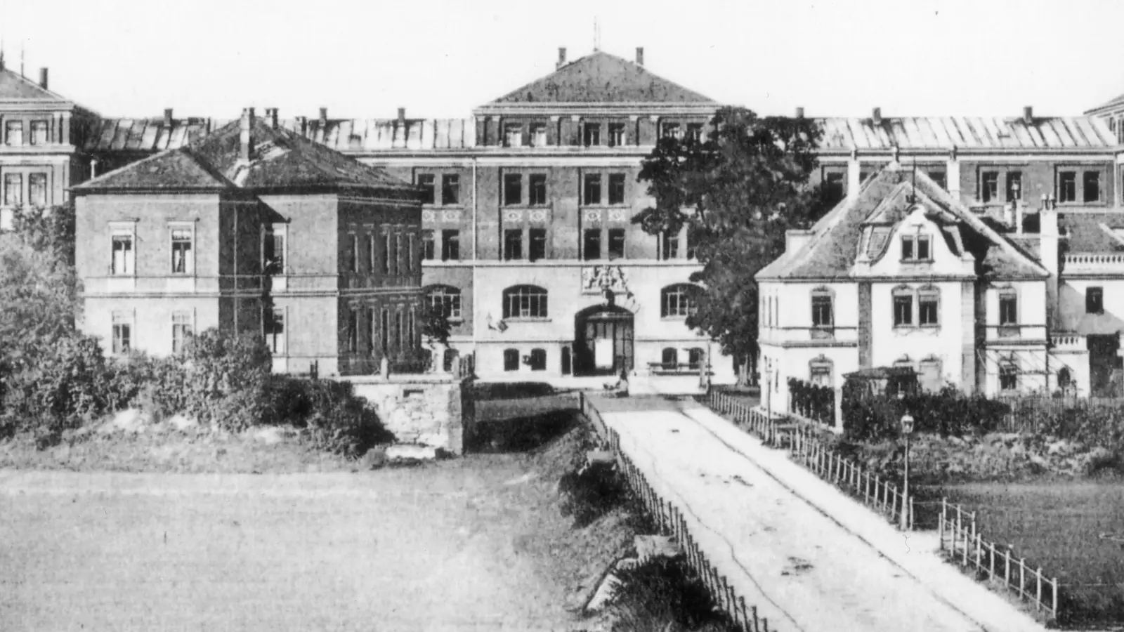 Auf dieser historischen Aufnahme ist im Vordergrund der Kasernendamm zu sehen, auf dem sich am 15. Juli 1926 eine größere Menschenmenge versammelt, um das Hochwasser der Rezat anzusehen. Im Hintergrund die Hindenburgkaserne, wo sich heute die Hochschule befindet. (Repro: Winfried Vennemann)