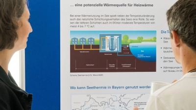 Besucher der Abschlussveranstaltung betrachten das Schema einer Seethermie-Anlage.  (Foto: Tobias Hase/dpa)