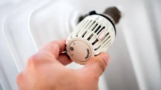 Ein Mann dreht in einer Wohnung am Thermostat einer Heizung. (Foto: Hauke-Christian Dittrich/dpa/Symbolbild)