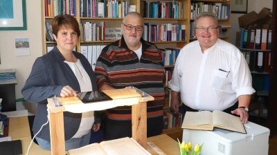 Mit einem eigens gebauten Holzgestell digitalisierten Heike Horn und Harald Beck das Buch aus den 30er Jahren. Der Wernsbacher Pfarrer Dr. Johannes Wachowski ist von dem Projekt angetan (von links). (Foto: Oliver Herbst)