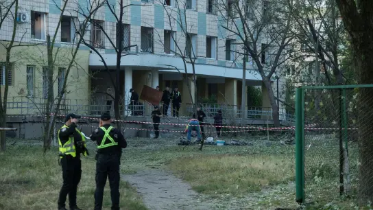 Polizisten in Kiew inspiziert ein Gebäude, das bei einem russischen Nachtangriff beschädigt wurde. (Foto: Wladyslaw Musiienko/AP/dpa)