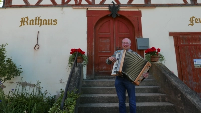 Ulrich Lutz spielt auf seinem Akkordeon vor dem Rathaus in Aufkirchen, während seine Zuhörer bereits unter der Dorflinde sitzen. (Foto: Roman Kocholl)