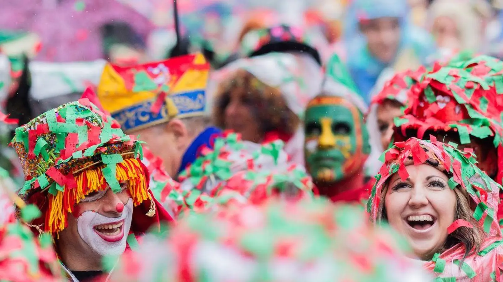 Karnevalisten sind komplett mit nassem Konfetti bedeckt und feiern die Eröffnung des Straßenkarnevals in Köln. (Foto: Rolf Vennenbernd/dpa)