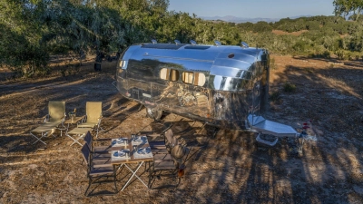 Amerikanisches Idyll: Der luxuriöse E-Caravan Bowlus Volterra wurde an einem lauschigem Plätzchen aufgestellt - der Champus ist schon kaltgestellt. (Foto: Bowlus/dpa-tmn)