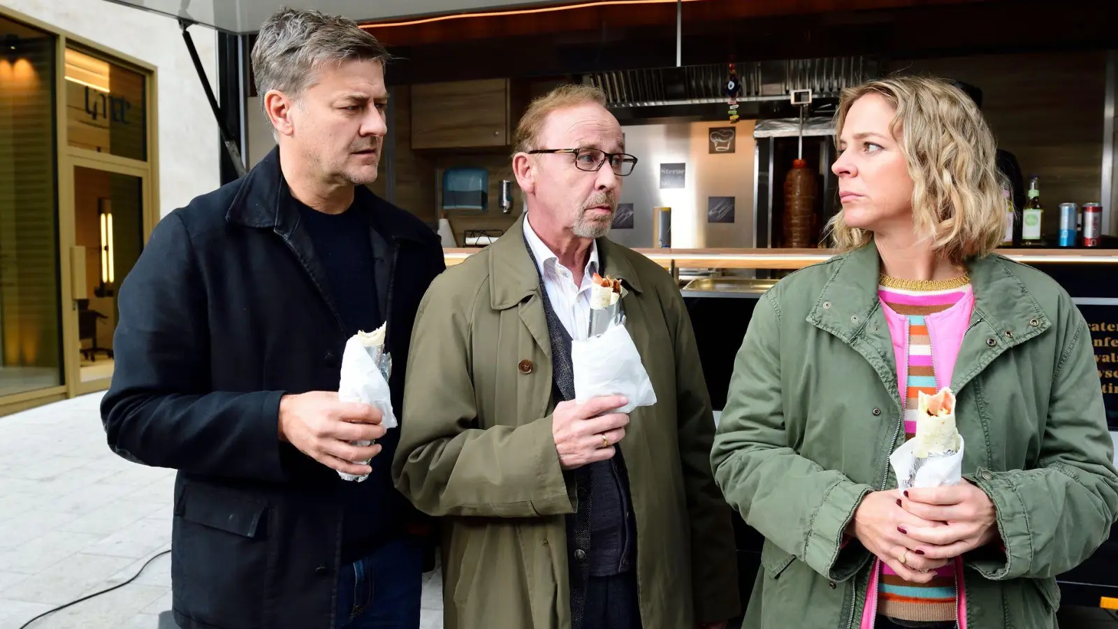 Harald Neuhauser (l, Marcus Mittermeier), Ludwig Schaller (Alexander Held) und Angelika Flierl (Bernadette Heerwagen) stehen vor einem Imbissstand. (Foto: Jürgen Olczyk,/ZDF/dpa)