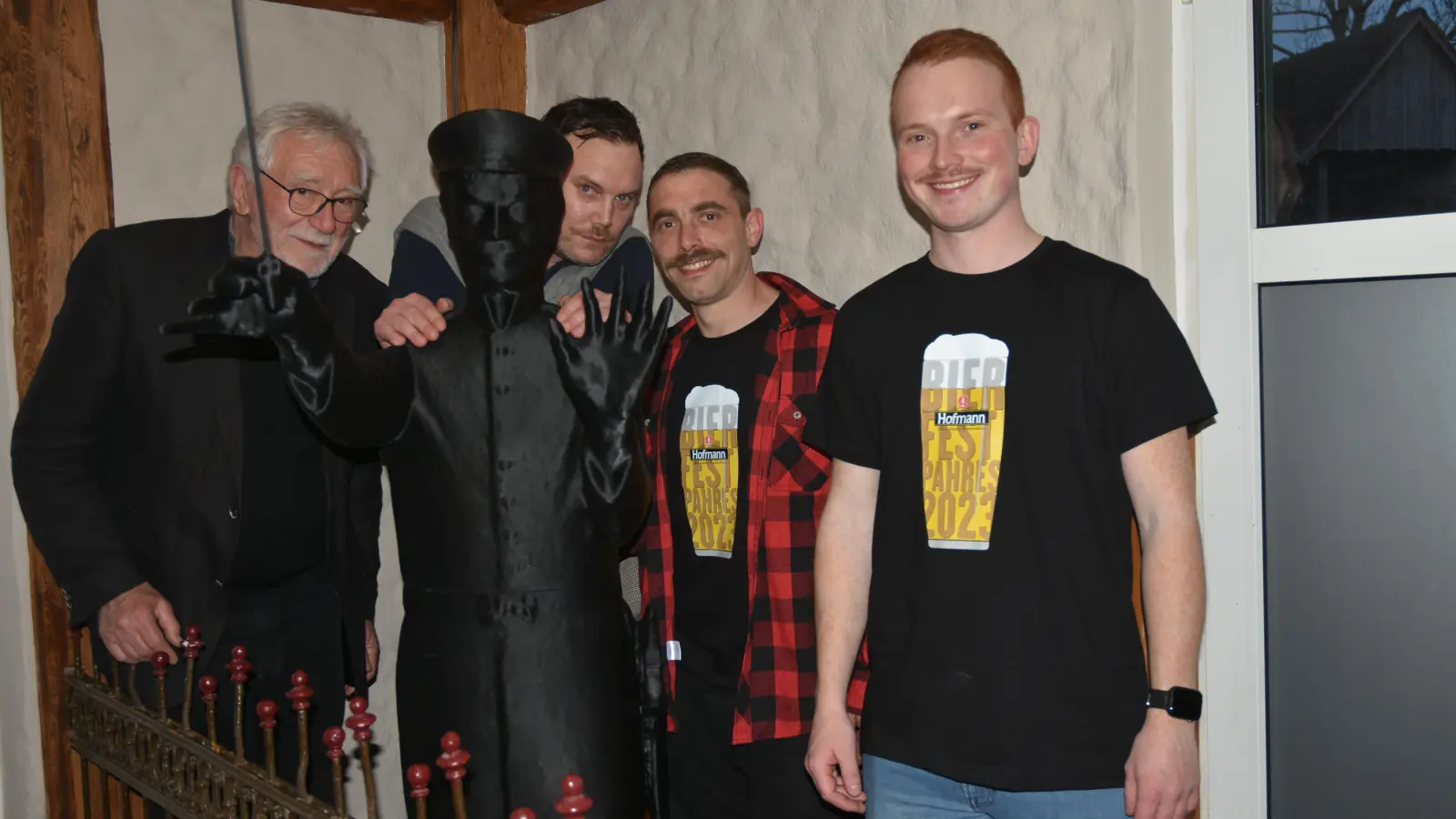 Vom ersten Stock aus schwingt Adolf Scherzer den Dirigentenstab über die Kneipe. Altbürgermeister Dr. Wolfgang Mück (links) referierte über den Schöpfer des Bayerischen Defiliermarsches. Sichtlich Freude hatten die Kneipenbetreiber Markus Fischer, Sven Perlwitz und Maximilian Hanke (weiter von links). (Foto: Anita Dlugoß)