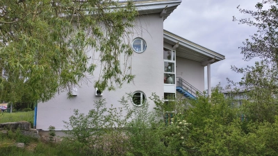 An die Ostseite der Merkendorfer Schule soll der Anbau gesetzt werden, um Platz für die Ganztagsbetreuung zu haben. Hinter den Büschen ist der naheliegende Kindergarten „Unterm Regenbogen” zu sehen.  (Foto: Robert Maurer)