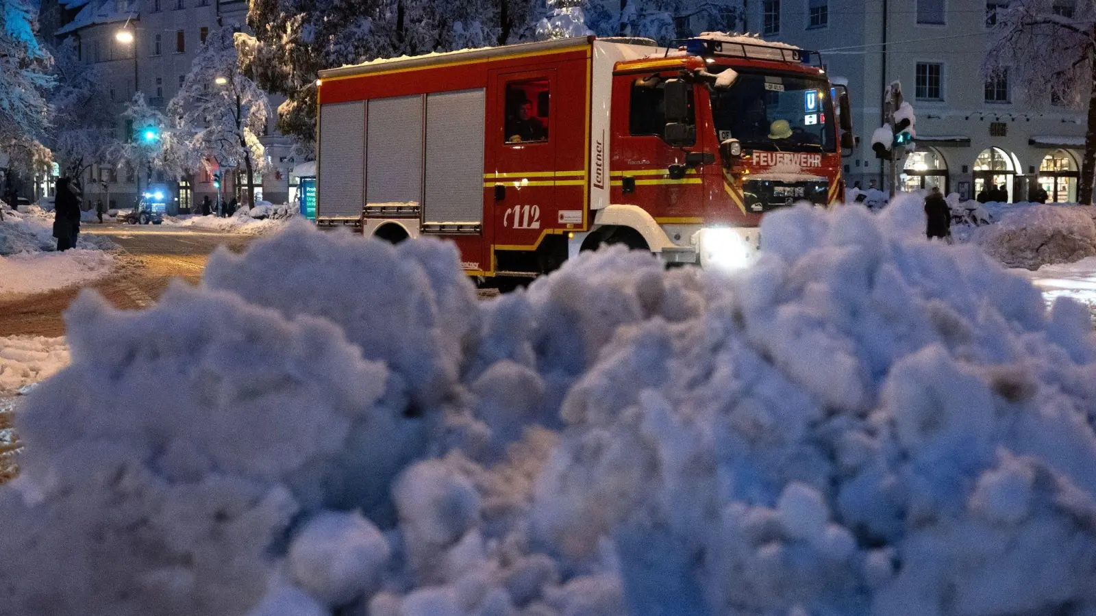 Ein Feuerwehrauto fährt hinter einem zusammengeräumten Schneehaufen entlang. (Foto: Sven Hoppe/dpa)