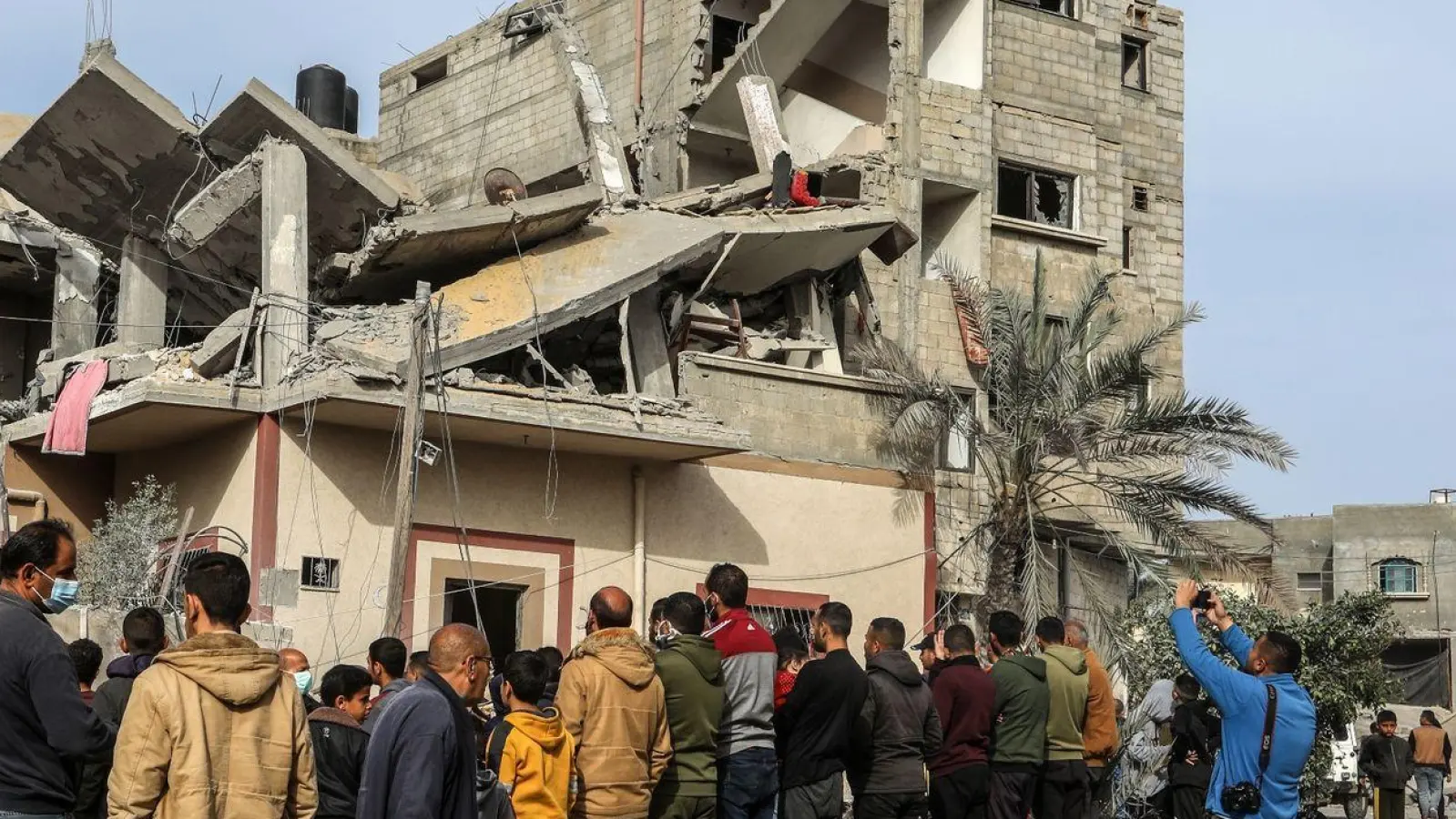 Menschen versammeln sich nach einem israelischen Luftangriff in Rafah um das zerstörte Haus einer Familie. (Foto: Abed Rahim Khatib/dpa)