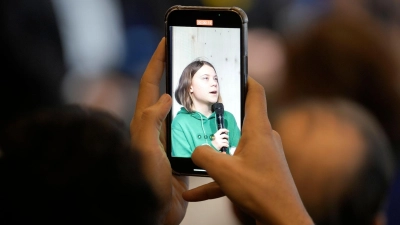 Während einer Pressekonferenz ist Greta Thunberg, Klimaaktivistin aus Schweden, auf dem Display eines Mobiltelefons zu sehen. (Foto: Markus Schreiber/AP/dpa)