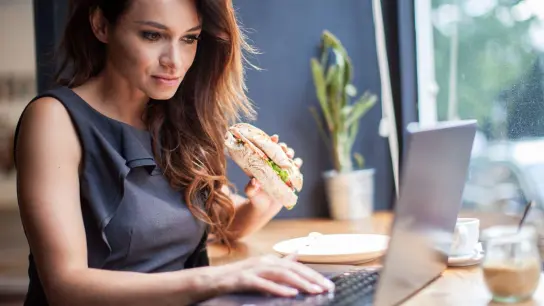 Zu den E-Mails ein Snack: Ob das Essen am Schreibtisch im Büro erlaubt ist, fragt man am besten den Arbeitgeber. Ein generelles gesetzliches Verbot gibt es aber nicht. (Foto: Christin Klose/dpa-tmn)