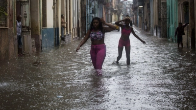 Zwei Frauen waten durch Hochwasser in Kubas Hauptstadt Havanna. (Foto: Irene Perez/TheNEWS2 via ZUMA Press Wire/dpa)