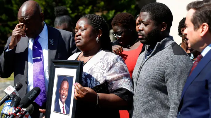 Caroline Ouko mit einem Porträt ihres getöteten Sohnes Irvo Otieno. Neben ihr stehen ihre Anwälte und ihr älterer Sohn Leon Ochieng. (Foto: Daniel Sangjib Min/Richmond Times-Dispatch/AP/dpa)
