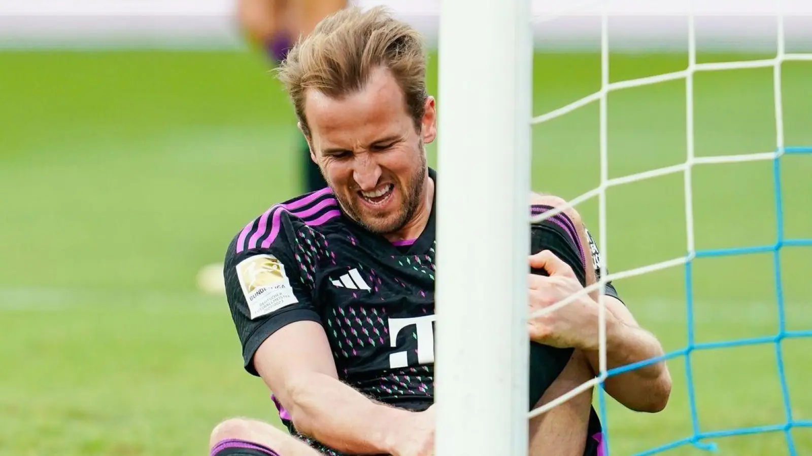Harry Kane von München sitzt mit schmerzverzerrtem Gesicht auf dem Rasen. (Foto: Uwe Anspach/dpa)