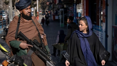 Ein Taliban-Kämpfer steht in Kabul Wache, während eine Frau vorbeiläuft. (Archivbild) (Foto: Ebrahim Noroozi/AP/dpa)
