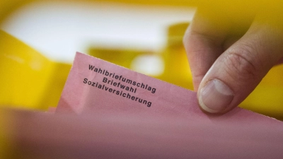 Ein Besucher eines Presserundgangs zieht in einer Lagerhalle in Berlin einen Wahlbrief aus einer Kiste. (Foto: picture alliance / Lino Mirgeler/dpa)
