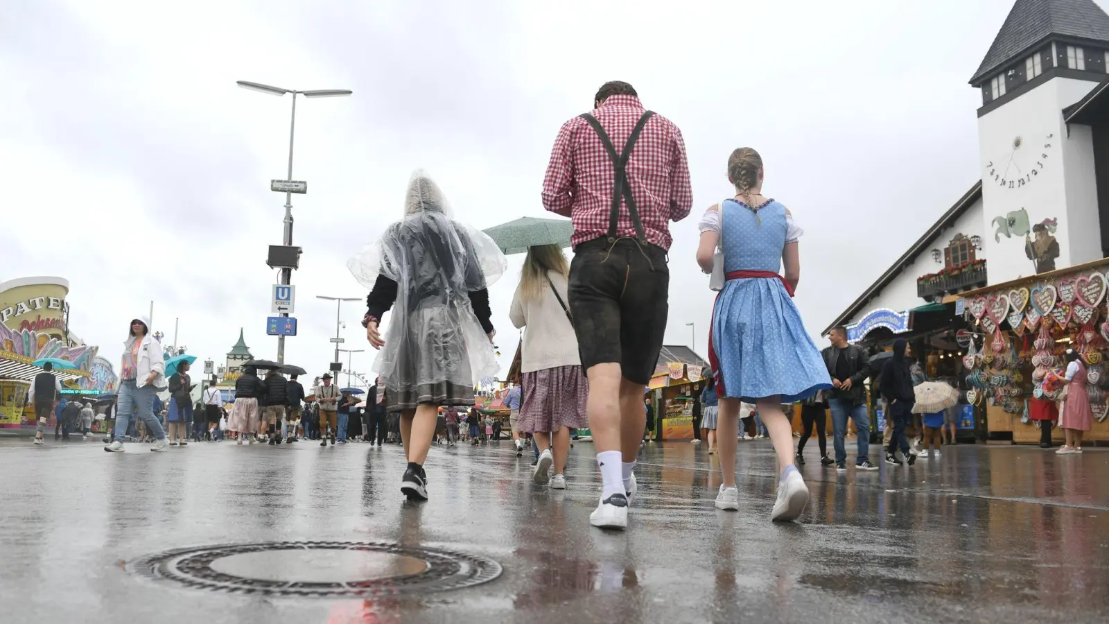 Besucher gehen bei Regenwetter über die Theresienwiese. (Foto: Felix Hörhager/dpa)