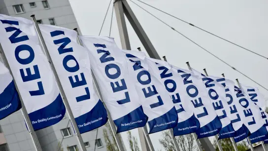 Fahnen mit dem Logo der Leoni AG wehen im Wind. (Foto: Daniel Karmann/dpa/Archivbild)
