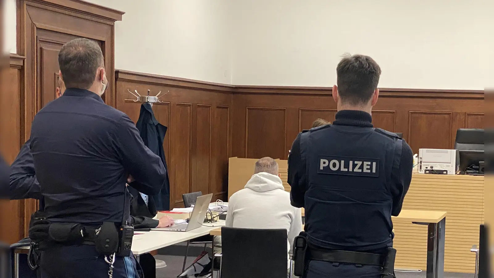 Polizisten haben im Gerichtssaal ein waches Auge auf den Angeklagten, der zudem Fußfesseln trägt. Sie schirmen ihn auch vor möglichen Angriffen von Zuhörern ab.  (Foto: Manfred Blendinger)