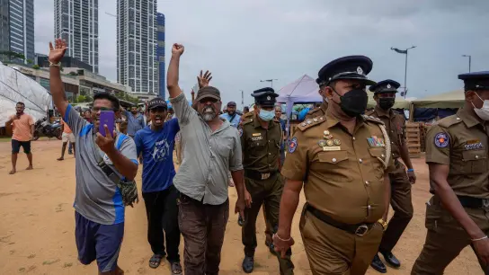 Demonstranten reagieren auf eine Lautsprecherdurchsage der Polizei, in der sie aufgefordert werden, den Ort der monatelangen Proteste gegen die Regierung vor dem Büro des Präsidenten zu verlassen. (Foto: Eranga Jayawardena/AP/dpa)