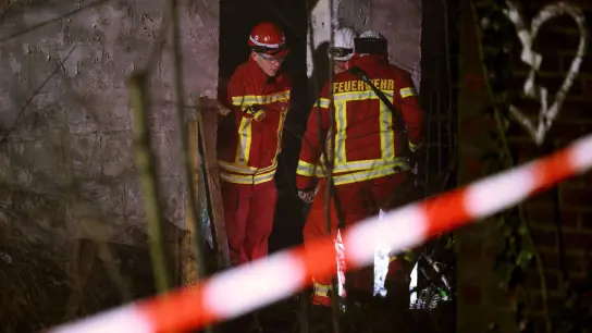 Rettungskräfte beraten vor eine Gebäude, in dem sich Personen in einem Tunnel verschanzt haben. (Foto: David Young/dpa)