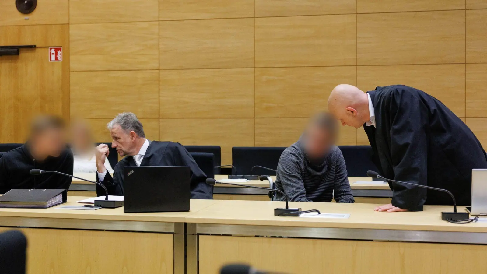 Christian Thüner (2.v.l) und Jerrit Schöll (r), die Verteidiger der Angeklagten, sprechen mit ihren Mandanten in einem Saal des Landgericht Bielefeld zum Auftakt im Prozess um ein illegales Motorradrennen mit Todesfolge. (Foto: Friso Gentsch/dpa)