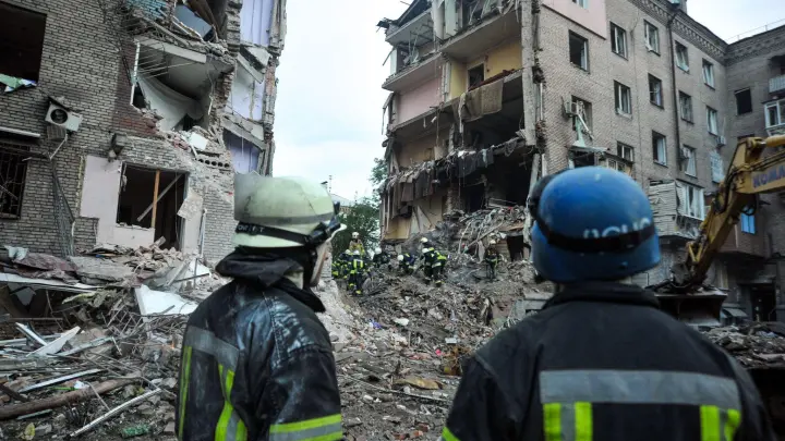 Rettungskräfte schauen auf die Trümmer eines zerstörten Wohnhauses in Saporischschja. (Foto: -/Ukrinform/dpa)