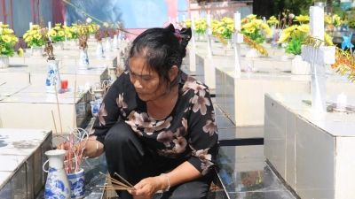 Nguyen Thi Nhiem zündet Räucherstäbchen auf einem Friedhof an und betet für die Seelen der ungeborenen Kinder. (Foto: Bac Pham/dpa)