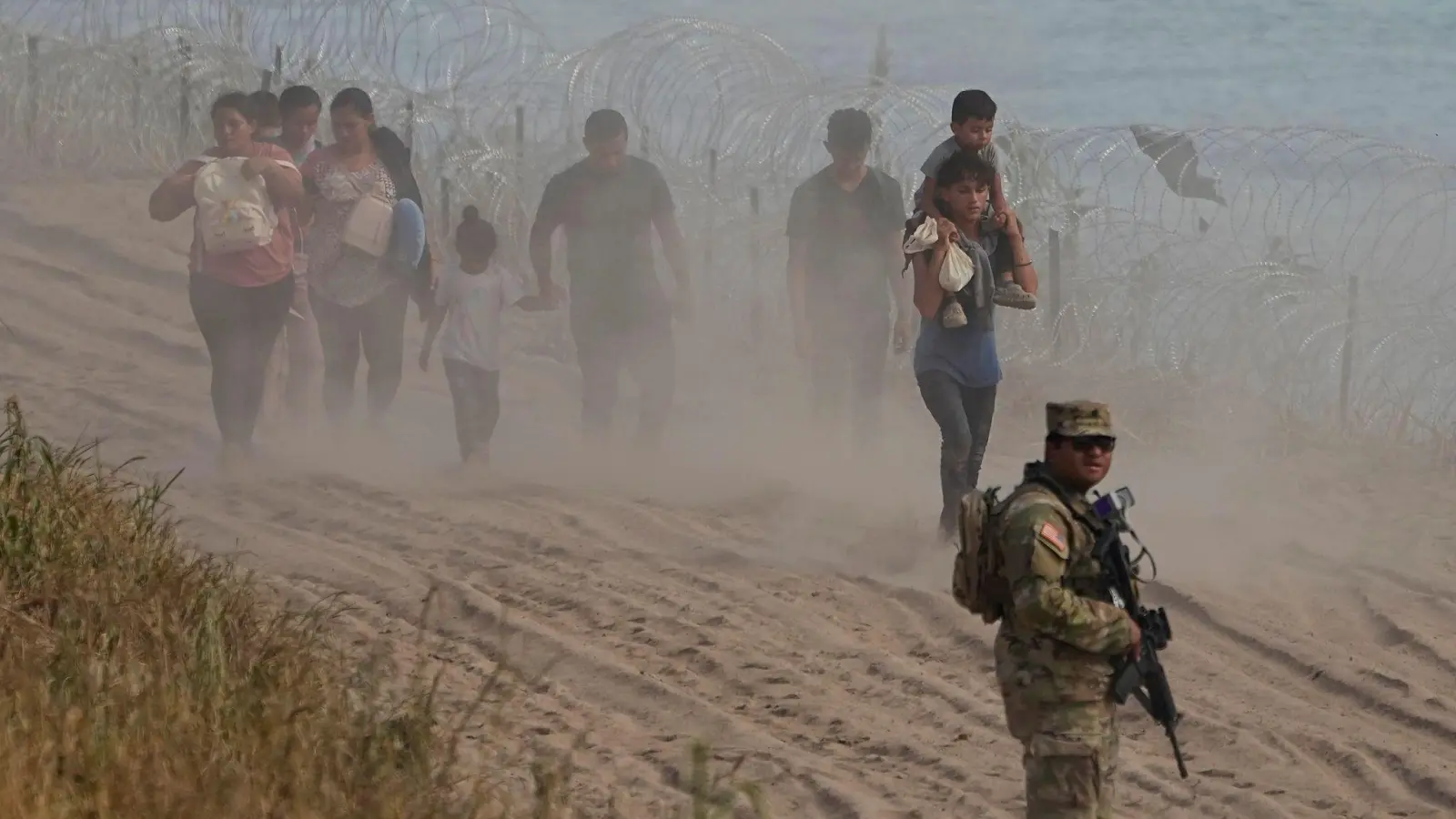 Ein texanischer Wachmann neben Menschen, die den Rio Grande von Mexiko aus in die USA überquert haben. (Foto: Eric Gay/AP)