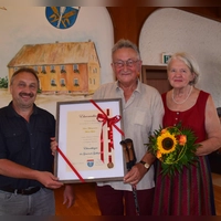 Bürgermeister Jürgen Trabert (links) durfte Altbürgermeister Werner Pfadler zum Ehrenbürger der Gemeinde Gollhofen ernennen. Für Ehefrau Christa Pfadler gab es Blumen. (Foto: Gerhard Krämer)