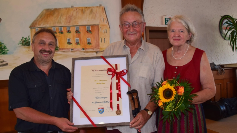 Bürgermeister Jürgen Trabert (links) durfte Altbürgermeister Werner Pfadler zum Ehrenbürger der Gemeinde Gollhofen ernennen. Für Ehefrau Christa Pfadler gab es Blumen. (Foto: Gerhard Krämer)